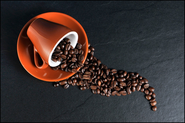 A cup and saucer with coffee beans spilling out of it