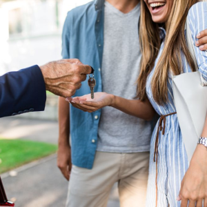 lady holding out hand to receive a key from realtor