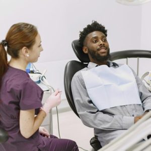 A person sitting in a chair with a dentist in the background