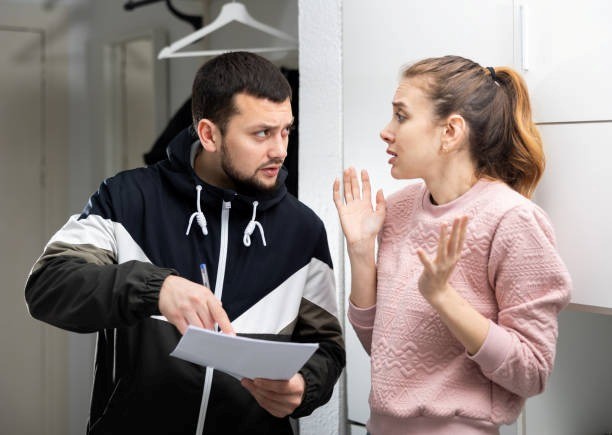man talking to frightened woman pointing to papers