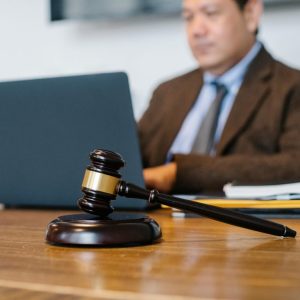 gavel sitting on desk with man looking at computer in the background