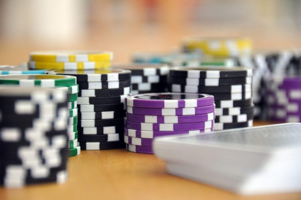 close up of black and purple poker chips with a stake of cards