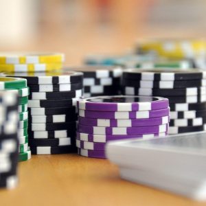 close up of black and purple poker chips with a stake of cards