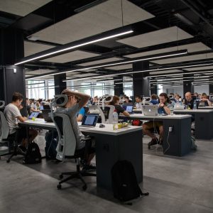 A spacious open office filled with people focused on their computers, collaborating in a professional environment.