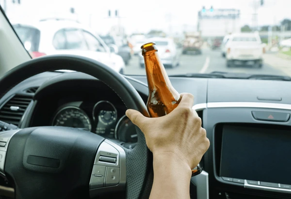 someone driving with a bottle in their hand on the wheel