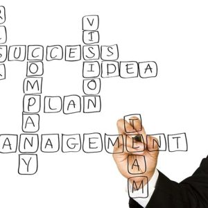 man writing management words in a crossword puzzle