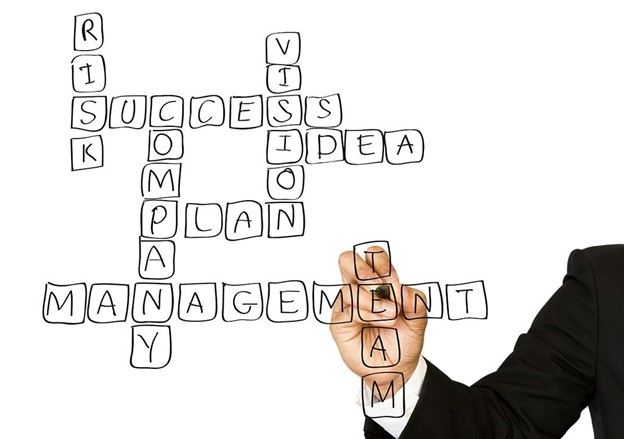 man writing management words in a crossword puzzle