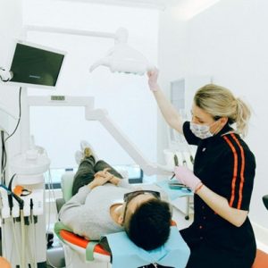dentist pulling the light closer to patient while looking at patient