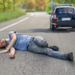 man lying in road after car hit