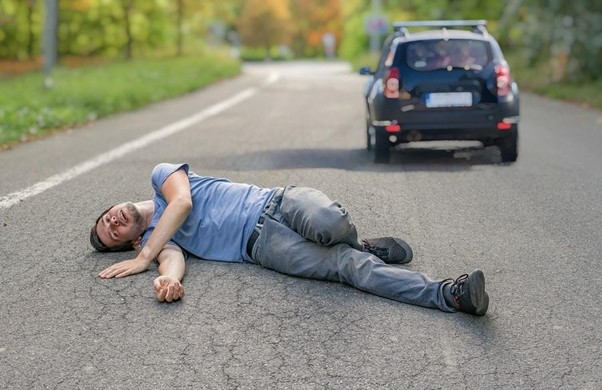 man lying in road after car hit
