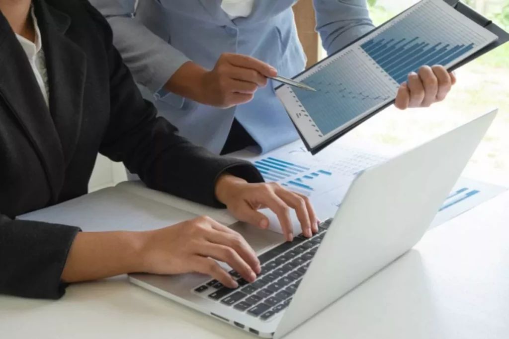 someone typing on a laptop and another holding an ipad