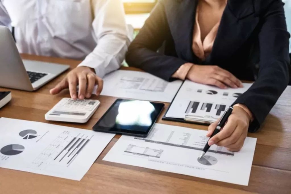 two people at a table using a calculator and looking at graphs