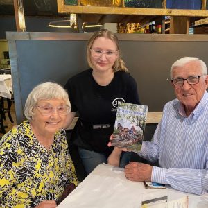 Sara-anna Copeland, center, welcomes Delene and Jasper Lee of Athens, Georgia, to 303 Jefferson, a must-stop for the couple when they visit Clinton. Lee, who grew up in the Clinton-Tinnin area, displays a copy of his latest book, William Walter.