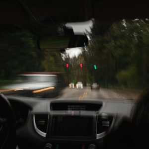 person driving in a car with car passing at a stop light