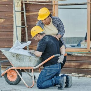 construction workers looking at the bag in a wheel barrow