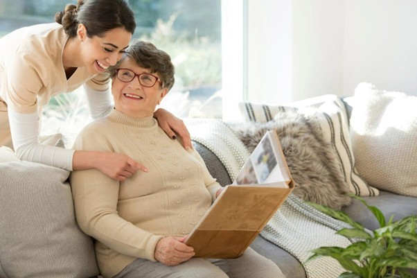 nurse looking over shoulder of senior adult woman looking at album