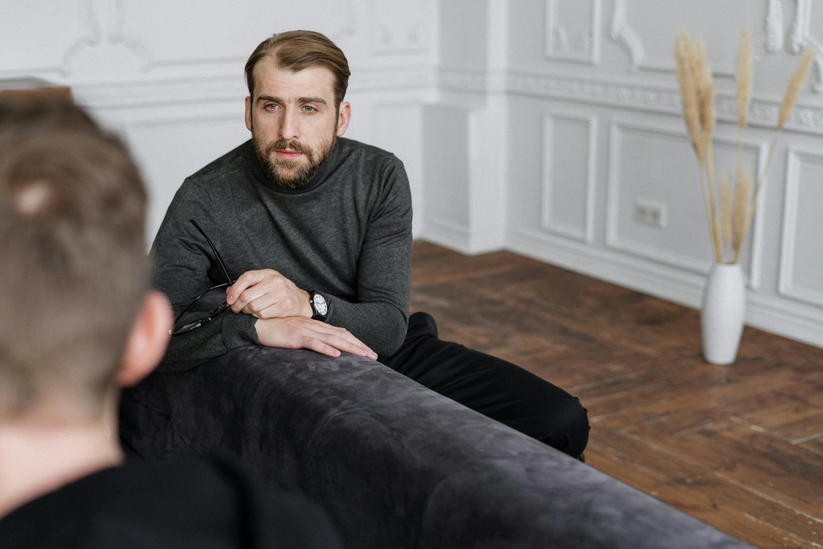 man in gray sweater sitting on a couch