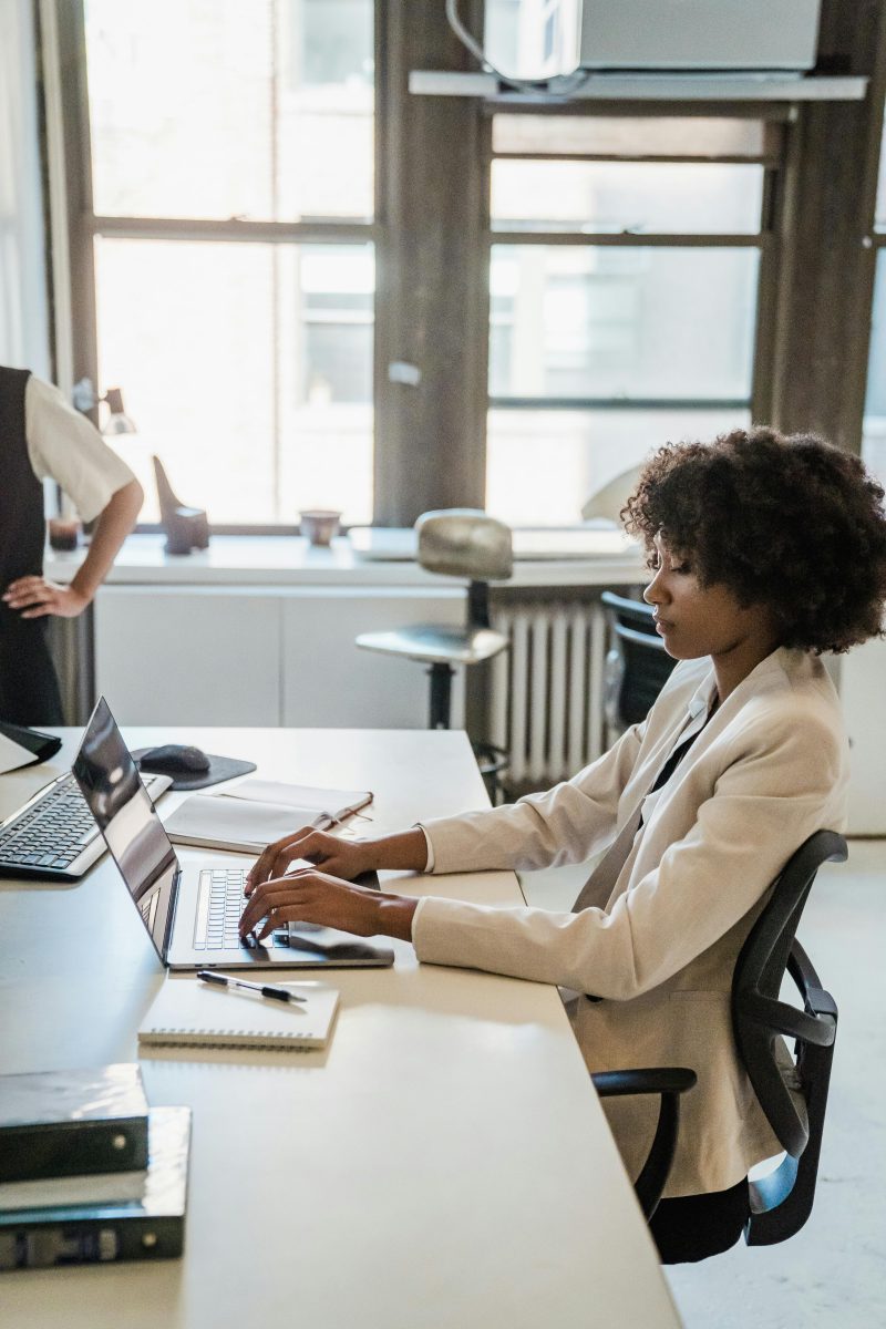 woman sitting at a desk typing on her laptop