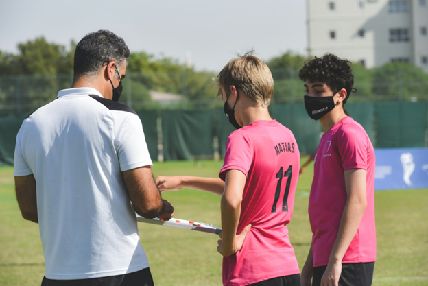 soccer coach and players wear mask while reviewing plays