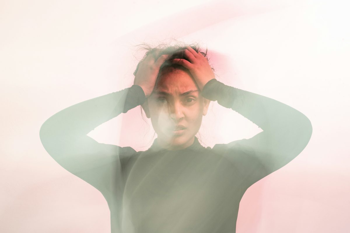 woman in gray turtleneck long sleever shirt with her hands on her hand and a worried face