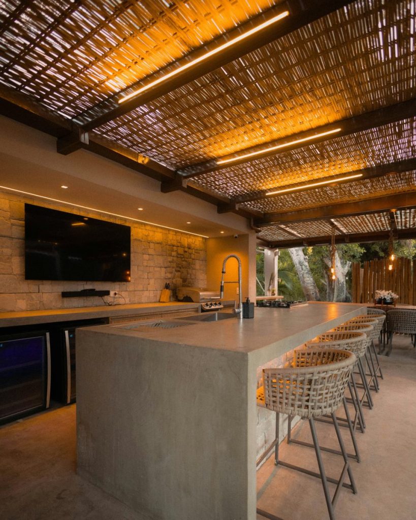 modern outdoor kitchen with tv, bar, and seating area