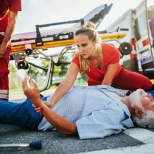 man laying on ground with nurses and cart in background
