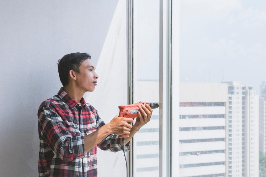 man with drill fixing a window