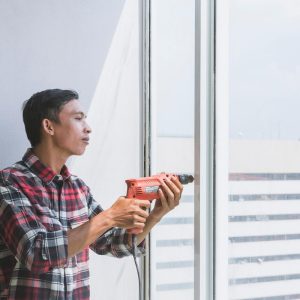 man with drill fixing a window