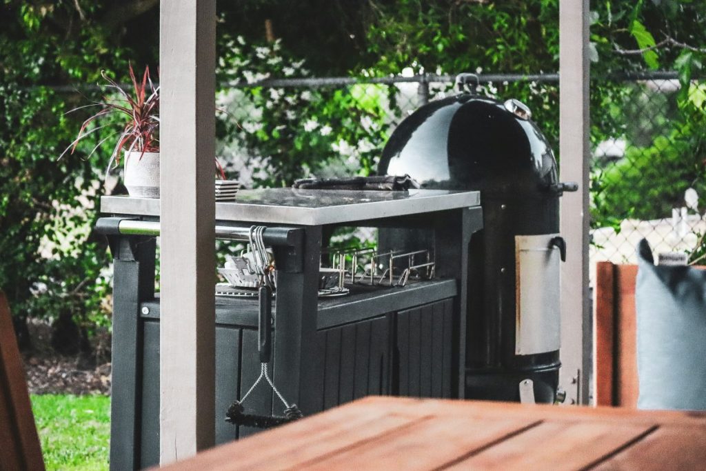 close up of outside grill and smoker with utensils on a table