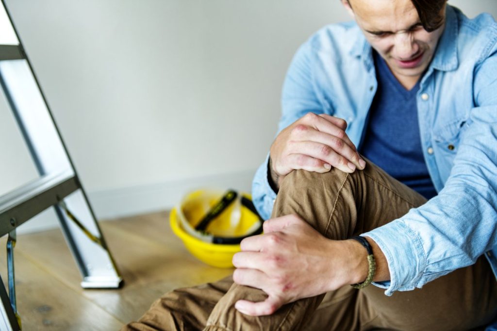 man holding his leg after a fall off a ladder