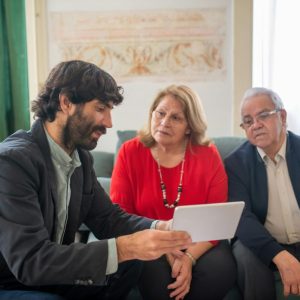broker presenting an offer to an elderly couple on a tablet