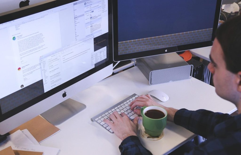 man using apple computer with coffee and keyboard