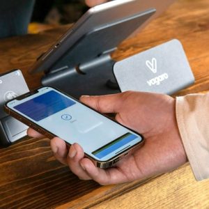 close up of hand holding phone over a tap payment system