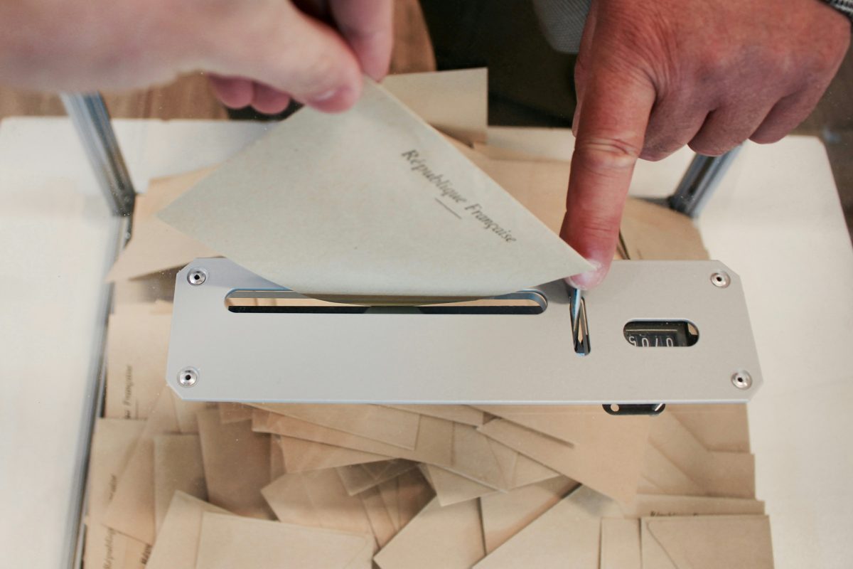 person holding a white paper on a white machine on a white table