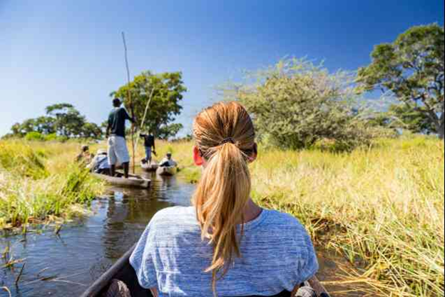 people in a boat going down a small water path