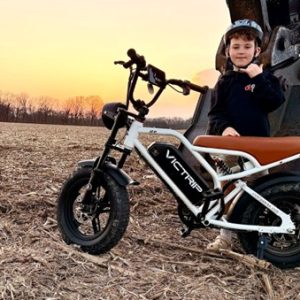 kid with helmet standing beside electric bike in open field