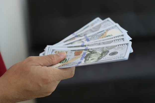 close up of a hand holding a stack of 100 dollar bills