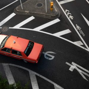 red car on road way turning left