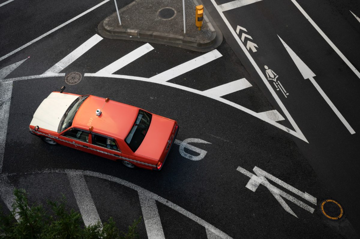 red car on road way turning left