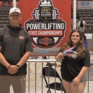 Clinton High School’s head girls’ powerlifting coach Patrick Ezell and Clinton senior Allison Herron celebrated her record-setting performance on March 28 at the MHSAA Class 7A State Meet at the Mississippi Coliseum in Jackson.