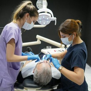 dentist and dental hygienist clean male patient's mouth