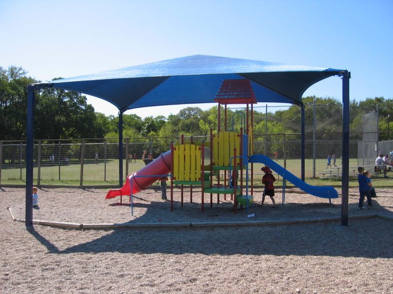 A playground with sliding equipment under a shade.