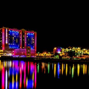 colorful lights reflect off of water near coastal casino