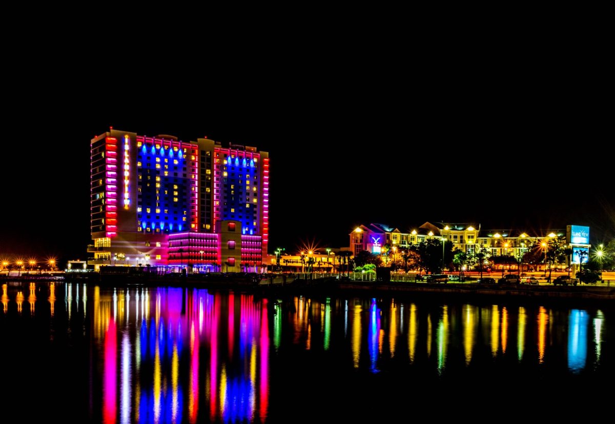 colorful lights reflect off of water near coastal casino