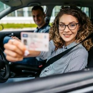 woman holding her license out of the car window