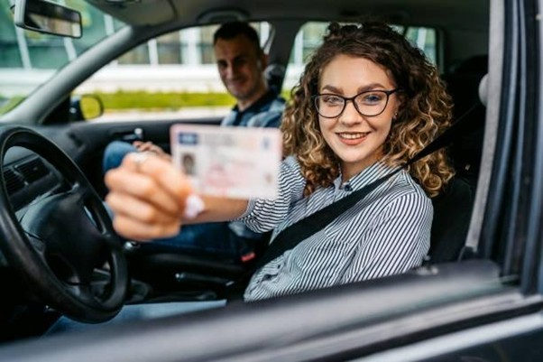 woman holding her license out of the car window