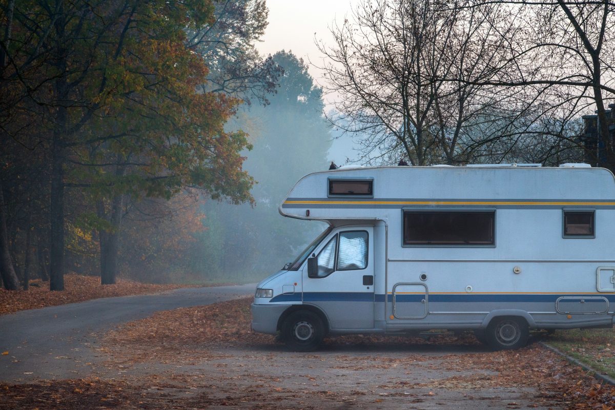 Old camper van parked on a foggy road on a cold autumn morning