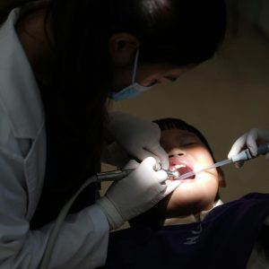 kid at dentist with dentist looking in his mouth using suction and water