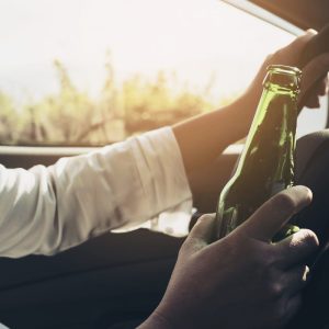 woman holding a beer bottle while driving