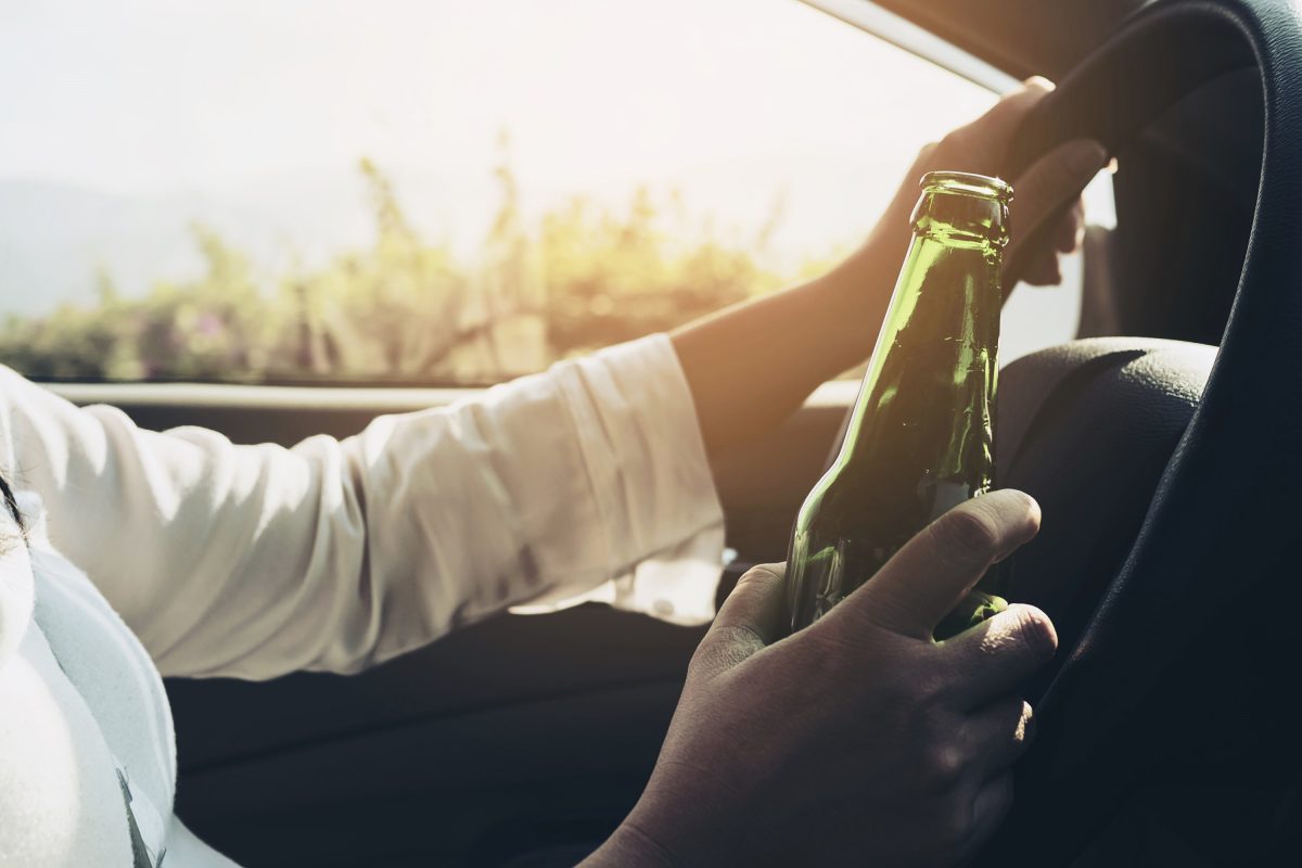 woman holding a beer bottle while driving